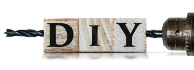 DIY metninin (kendiniz yapın) yakın plan, ahşap bloklardan ve siyah uçlu bir elektrikli matkap, kopyalama alanı ile beyaz arkaplan izole.