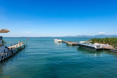 Lazise ve Bardolino köyleri arasında sürat tekneleri bulunan Garda Gölü kıyısındaki küçük liman, Veneto, İtalya ve güney Avrupa 'daki turistik tatil beldeleri. Ufukta Lombardiya kıyısı. 