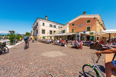 BARDOLINO, İtalya - 26 Mayıs 2021: Bardolino köyü şehir merkezi, Garda Gölü kıyısındaki turizm beldesi. Turistler, restoranlar ve pizzacılarla dolu bir gezinti. Verona ili, Veneto, İtalya, Avrupa.