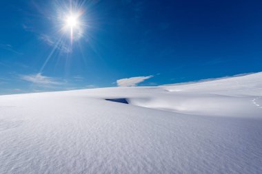 Toz karlı güzel kış manzarası bulutlu ve güneş ışınlı açık mavi gökyüzüne karşı. Lessinia Plateau (Altopiano della Lessinia), Regional Natural Park, Verona Eyaleti, Veneto, İtalya, Avrupa.