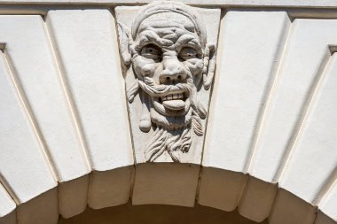 Brescia 'da. Ortaçağ Broletto Sarayı (Palazzo Broletto veya Palazzo del Governo), XII-XI. Anahtar taşlı beyaz taş kemer ve tuhaf bir insan maskesi. Lombardiya, İtalya, Avrupa.