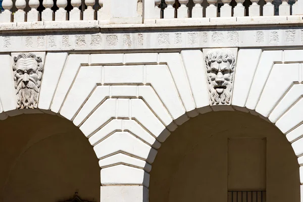 Brescia 'da. Ortaçağ Broletto Sarayı (Palazzo Broletto veya Palazzo del Governo), XII-XI. Kilit taşlı iki beyaz taş kemer ve tuhaf insan maskeleri. Lombardiya, İtalya, Avrupa.