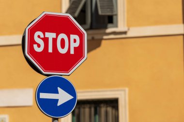 Close-up of an one way and a stop road sign with a residential building in the background, Brescia, Italy, Europe.