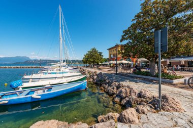 CISANO DI BARDOLINO, İtalya - 26 Mayıs 2021: Cisano köyünün tekneleri demirli küçük limanı. Garda Gölü kıyısındaki turizm beldesi (Lago di Garda). Bardolino belediyesi, Verona, Veneto, İtalya.