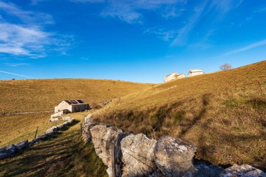 Lessinia Platosu Bölgesel Parkı 'nda (Altopiano della Lessinia) sonbaharda eski çiftlik evleri ve otlaklarıyla yürüyüş yolu. Bosco Chiesanuova belediyesi, Verona, Veneto, İtalya, Avrupa.