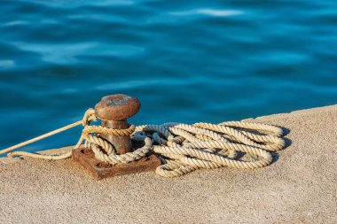 Close-up of a rusty mooring bollard with ropes or hawsers on the quay of the port. Gulf of La Spezia, Liguria, Italy, Europe.