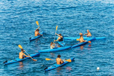 TELLARO, ITALY - JULY 28, 2022: Large group of kayakers in the blue Mediterranean Sea, on a sunny summer day. Tellaro village, Gulf of La Spezia, Liguria, Italy, southern Europe.