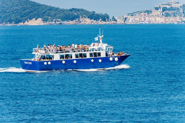 TELLARO, ITALY - JULY 15, 2022: Blue ferry crowded with tourists in motion in the Gulf of La Spezia to the Cinque Terre, Porto Venere or Portovenere town and Palmaria island, Liguria, Italy, Europe.