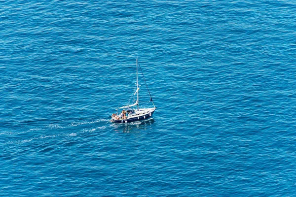 Aerial view of a small sailing boat with a small group of people on board, in the blue Mediterranean Sea, Gulf of La Spezia, Liguria, Italy, southern Europe.
