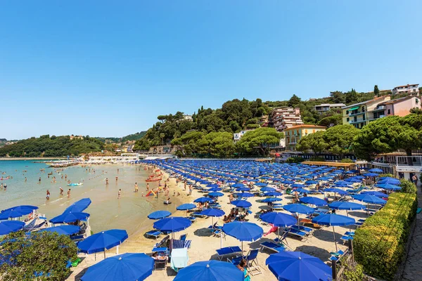 LERICI, ITALY - JULY 16, 2022: Beach of Lerici Town with many umbrellas, tourist resort on the coast of the Gulf of La Spezia, Liguria, Italy, Europe. On background the small village of San Terenzo.