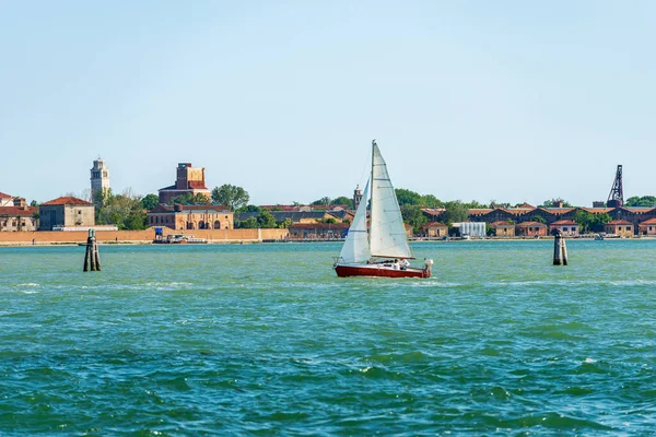 White and red sailing boat in motion in the Venetian Lagoon on a sunny spring day. Venice, Veneto, Italy, southern Europe. UNESCO world heritage site.