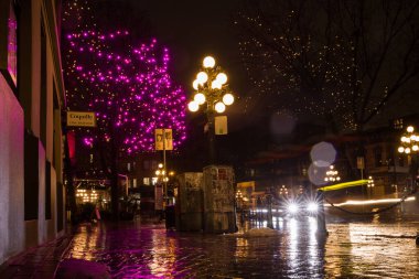 Vancouver British Columbia, Kanada. Gece, yağmurdan sonra şehrin ışığını aydınlattı. Şehir merkezindeki eski cadde binaları, çelenkler ve arabalar. Gece arkaplanı