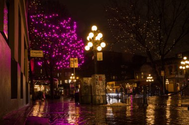 Vancouver British Columbia, Kanada. Gece, yağmurdan sonra şehrin ışığını aydınlattı. Şehir merkezindeki eski cadde binaları, çelenkler ve arabalar. Gece 01.08.2022