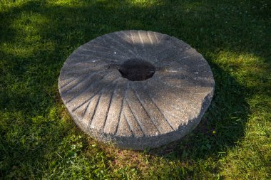 Millstones for grinding wheat or other grains. grinding stones. Old element of mill on green grass