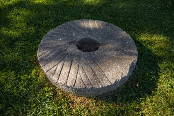 Millstones for grinding wheat or other grains. grinding stones. Old element of mill on green grass