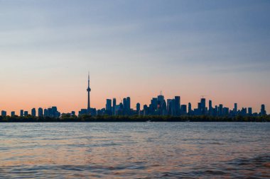 Toronto gökdelenli şehir manzarası, sakin göl suyu. Kentsel ufuk çizgisi geçmişi. Akşam vakti, gün batımı