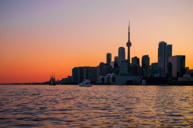 Toronto şehir merkezi gökdelenleri, beyaz yatı, eski yelkenlisi ve inanılmaz renkli günbatımı gökyüzü. Seyahat ve ulaşım