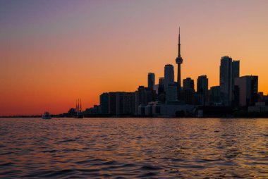 Toronto şehir merkezi gökdelenleri, beyaz yatı, eski yelkenlisi ve inanılmaz renkli günbatımı gökyüzü. Seyahat ve ulaşım