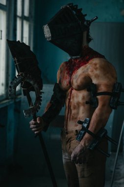 Karanlık odada elinde testere ve baltayla maskeli zombi canavarı görüntüsü olan kanlı bir adam. Cadılar Bayramı konsepti.