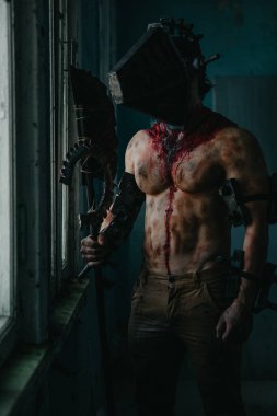 Karanlık odada elinde testere ve baltayla maskeli zombi canavarı görüntüsü olan kanlı bir adam. Cadılar Bayramı konsepti.