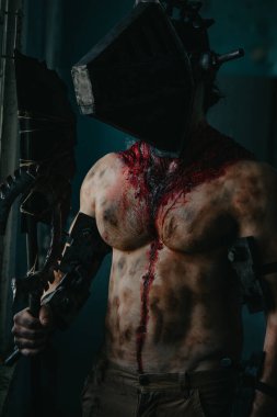 Karanlık odada elinde testere ve baltayla maskeli zombi canavarı görüntüsü olan kanlı bir adam. Cadılar Bayramı konsepti.