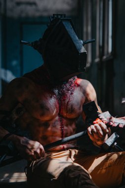 Kafasında maske olan zombi canavarın görüntüsü olan kanlı adam testereyle karanlık odada oturuyor. Cadılar Bayramı konsepti.