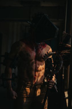 Karanlık odada elinde testere ve baltayla maskeli zombi canavarı görüntüsü olan kanlı bir adam. Cadılar Bayramı konsepti.