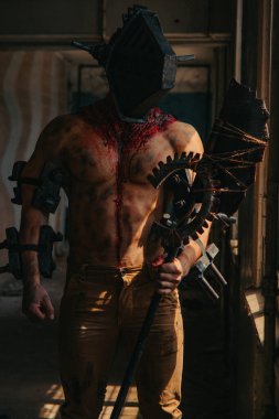 Karanlık odada elinde testere ve baltayla maskeli zombi canavarı görüntüsü olan kanlı bir adam. Cadılar Bayramı konsepti.