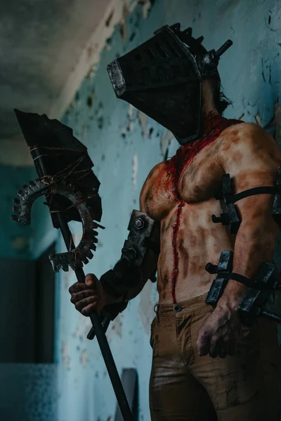 Karanlık odada elinde testere ve baltayla maskeli zombi canavarı görüntüsü olan kanlı bir adam. Cadılar Bayramı konsepti.