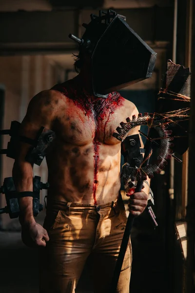 Karanlık odada elinde testere ve baltayla maskeli zombi canavarı görüntüsü olan kanlı bir adam. Cadılar Bayramı konsepti.