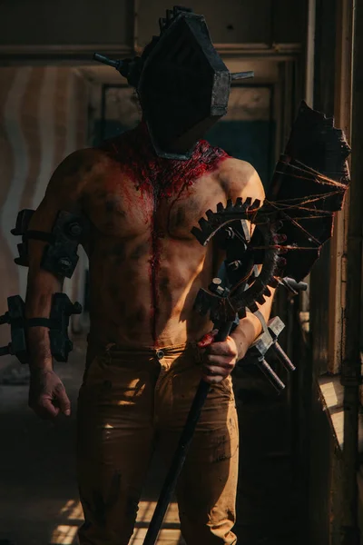 Karanlık odada elinde testere ve baltayla maskeli zombi canavarı görüntüsü olan kanlı bir adam. Cadılar Bayramı konsepti.