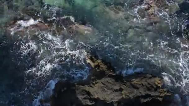 透明なターコイズブルーの海の水 スプラッシュ クレタ島のギリシャの島の岩の上の美しいドローンビュー — ストック動画