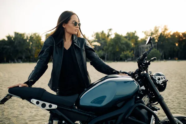 Young Woman Stands Black Motorbike Sunglasses Leather Jacket Sandy Beach — Stock Photo, Image