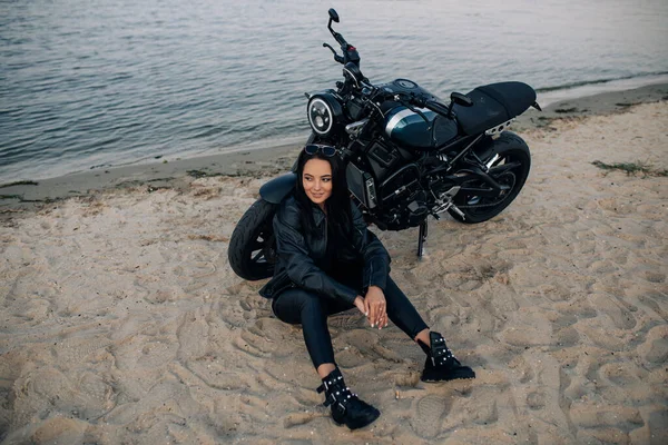 Jovem Mulher Senta Areia Perto Moto Preta Jaqueta Couro Calças — Fotografia de Stock