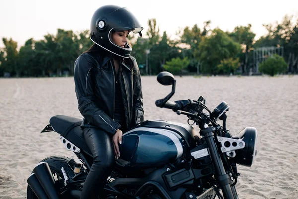 Молодая Женщина Сидит Черном Мотоцикле Шлеме Кожаной Куртке Среди Песчаного — стоковое фото