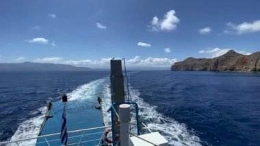 Denizde hareket eden gemiden, deniz köpüğünden ve gökyüzüne karşı dağlardan görüş..