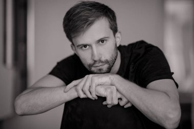 Sakallı genç düşünceli adamın siyah beyaz portresi.