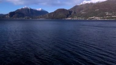 İtalya Gölü 'nün su yüzeyinin güzel drone görüntüsü Mavi gökyüzü, bulutlar ve karla kaplı Alpler mesafenin zirveleri.