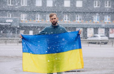 Genç kızgın adam ellerinde Ukrayna 'ya yapılan saldırı ve işgali protesto eden Ukrayna bayrağını tutuyor. Rus saldırganlık kavramı.
