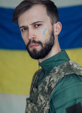 Yüzünde Ukrayna bayrağı olan çelik yelek giymiş öfkeli genç bir adamın portresi. Ukrayna 'da Rus askeri istilası kavramı. Ukrayna ve Avrupa 'da savaş.