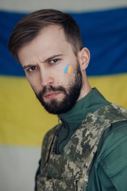 Yüzünde Ukrayna bayrağı olan çelik yelek giymiş öfkeli genç bir adamın portresi. Ukrayna 'da Rus askeri istilası kavramı. Ukrayna ve Avrupa 'da savaş.