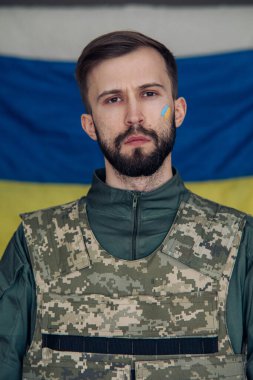 Yüzünde Ukrayna bayrağı olan çelik yelek giymiş öfkeli genç bir adamın portresi. Ukrayna 'da Rus askeri istilası kavramı. Ukrayna ve Avrupa 'da savaş.