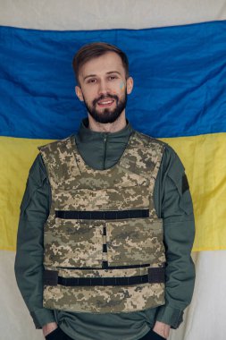 Ukrayna bayrağının arka planında çelik yelek giymiş genç bir adamın portresi. Ukrayna 'da Rus askeri istilası kavramı. Ukrayna ve Avrupa 'da savaş.