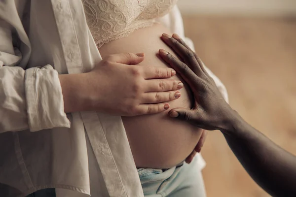 Χέρι Του Αφρικανού Αγγίζει Την Κοιλιά Της Καυκάσιας Εγκύου Γυναίκας — Φωτογραφία Αρχείου
