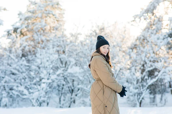在阳光明媚的冬日里 快乐的年轻微笑的女人走在雪地覆盖的松树丛中 — 图库照片