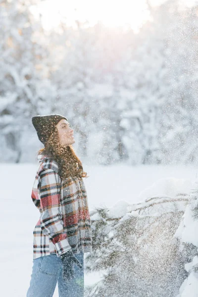 在阳光明媚的冬日里 一位快乐的年轻女子在白雪覆盖的松树丛中散步 — 图库照片
