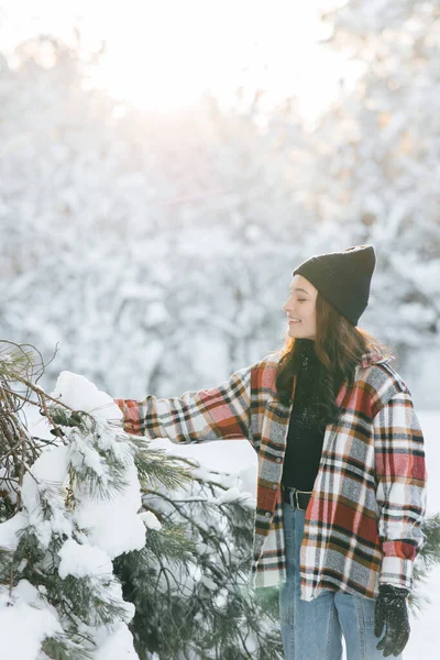 在阳光明媚的冬日里 快乐的年轻女子漫步在白雪覆盖的松树丛中 — 图库照片