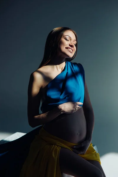 Happy Pregnant Woman Sits Dress Looks Ukrainian Flag Studio Dark — Stock Photo, Image