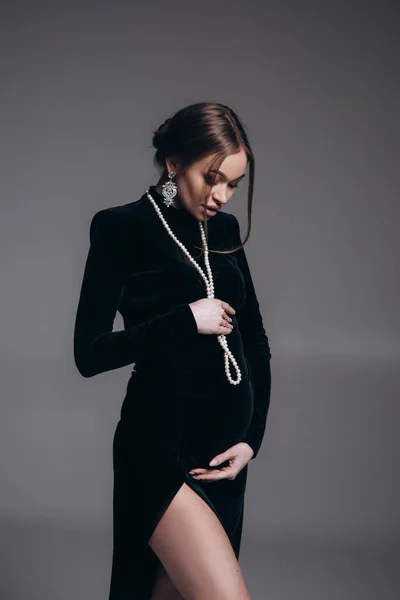 Gelukkig Zwangere Vrouw Staat Zwarte Jurk Met Kralen Studio Tegen — Stockfoto