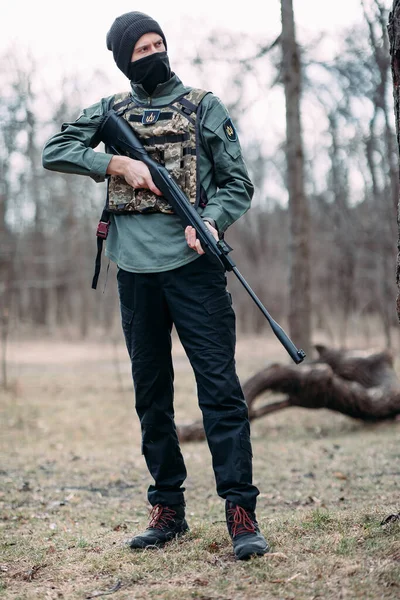 若い男が立ってポンプ銃彼の手の中に身に着けていた鎧や森の中のバラクラバ — ストック写真